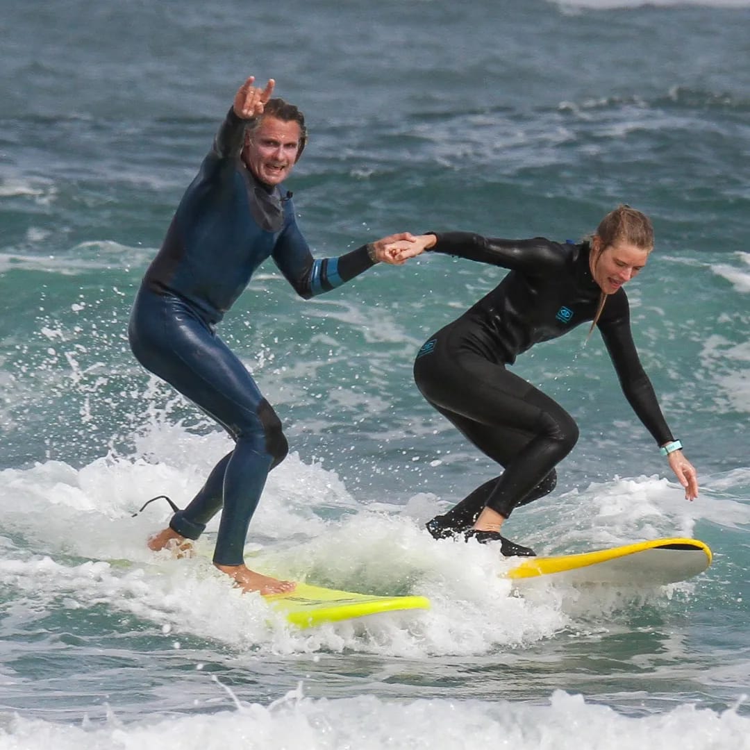 Surf Coach haciendo coger la primera ola a un turista